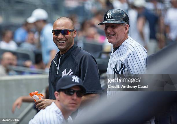 Derek Jeter of the New York Yankees and first base coach Mick Kelleher smile in the dugout during the game against the Detroit Tigers at Yankee...