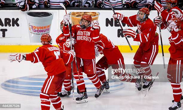 Matt Grzelcyk of the Boston University Terriers celebrates his overtime winning goal against the Northeastern Huskies with teammates Evan Rodrigues,...