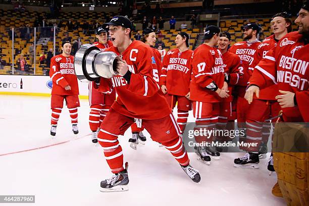 Matt Grzelcyk of the Boston Univeristy Terriers celebrates with the Beanpot Trophy after the Terriers defeat the Northeastern Huskies 4-3 during...