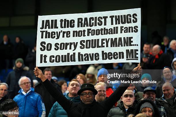Fan holds up a banner condemning racism during the Barclays Premier League match between Manchester City and Newcastle United at the Etihad Stadium...