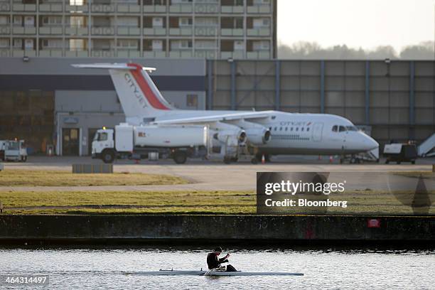 An Avro RJ85 passenger aircraft, operated by CityJet Ltd., a unit of Air France-KLM Group, stands on the tarmac as a rower paddles a single scull...