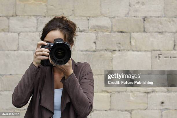 Portrait of a female photographer looking through the viewfinder of a Nikon D3 DSLR while on location in Bath, England, taken on August 14, 2013.