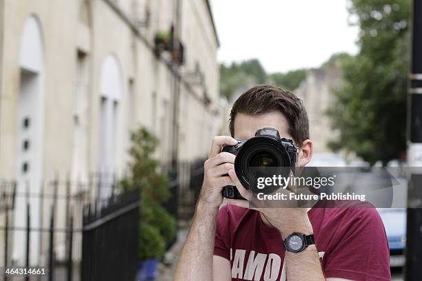 Portrait of a male photographer looking through the viewfinder of a Nikon D3 DSLR while on location in Bath, England, taken on August 14, 2013.