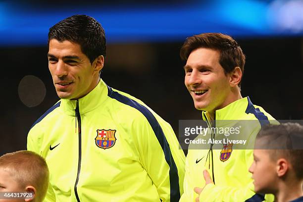 Luis Suarez and Lionel Messi of Barcelona share a joke as the teams line up during the UEFA Champions League Round of 16 match between Manchester...