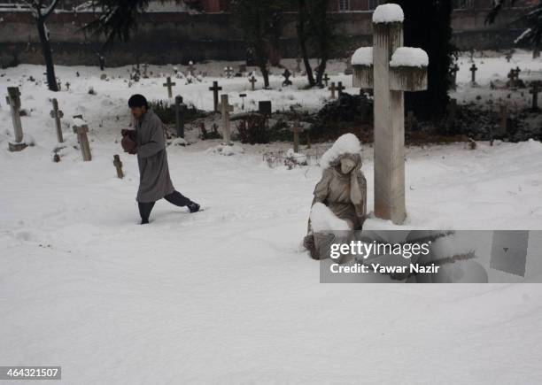 Kashmiri Muslim caretaker of Christian cemetery walks inside a graveyard during a snowfall on January 22, 2014 in Srinagar, Indian Administered...