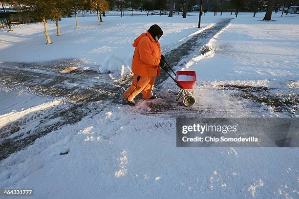 The Washington Metropolitan Area Transit Authority worker spreads ice melt on the sidewalk outside the Takoma Metro station January 22, 2014 in...