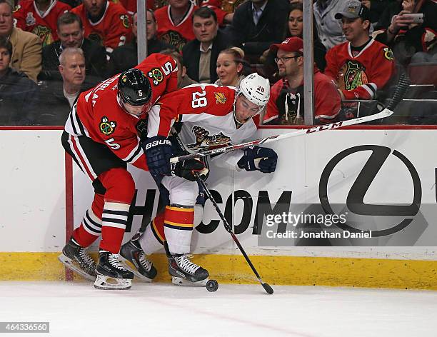 David Rundblad of the Chicago Blackhawks and Garrett Wilson of the Florida Panthers battle for the puck at the United Center on February 24, 2015 in...