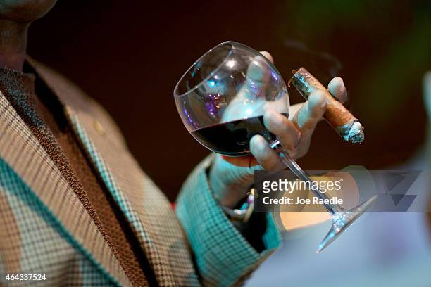 Cigar aficionado enjoys a glass or wine with a cigar during the opening gala night of the week-long International Habano Cigar Festival on February...