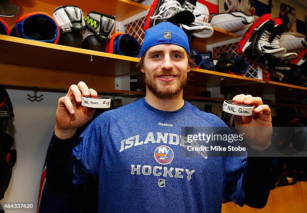 Kael Mouillierat of the New York Islanders holds the pucks that he scored his first career point on an assist and first career goal with in a game...