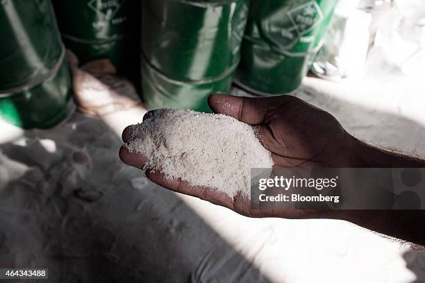 Worker holds a handful of quartz for a photograph in the mixing area at a Pooja Group Of Glass Industries factory in Ferozabad, Uttar Pradesh, India,...