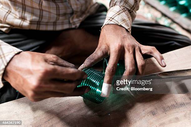 Worker cuts coils of glass with a diamond cutter into bangles at the Kohinoor Bangle Industries factory in Ferozabad, Uttar Pradesh, India, on...