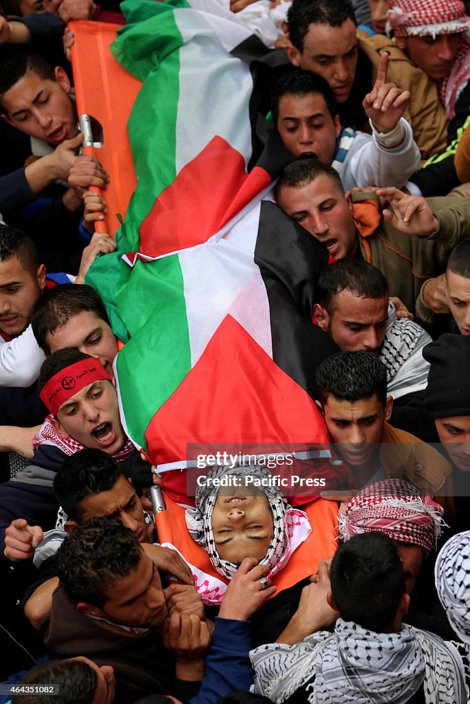 Palestinian men carry the body of a teenager killed by...