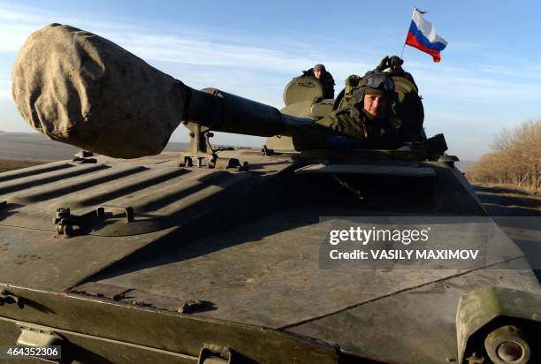 Russian flag flies near Pro-Russia militants sitting atop a 2S1 Gvozdika as a convoy of pro-Russian forces takes a break as they move from the...