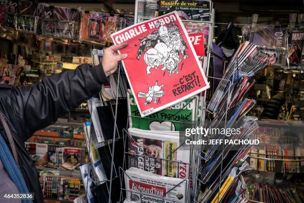 Man picks up the latest edition of French satirical weekly newspaper Charlie Hebdo at a newsstand on February 25, 2015 in Lyon. More than a month...