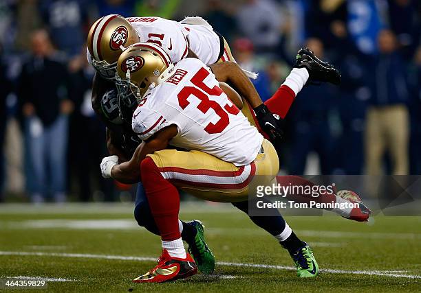 Wide receiver Doug Baldwin of the Seattle Seahawks is tackled by strong safety Donte Whitner and free safety Eric Reid of the San Francisco 49ers...