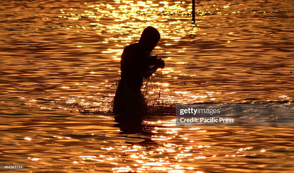 A devotee taking holydip during sunset at Sangam...