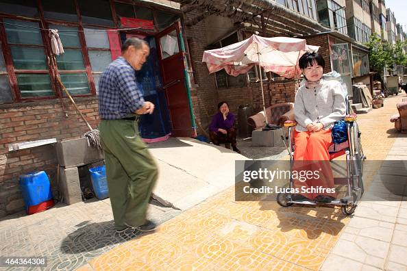 Li Yan Case A neighbor walks pass Li Yan sitting in her wheel-chair in a... News ...
