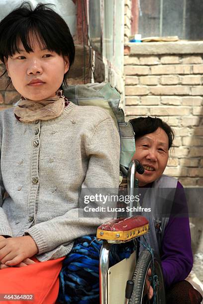 May 07: Li Yan sits in her wheel-chair while her mother Song Fengying seats behind it, outside their house on May 7, 2007 in Yinchuan, Ningxia...