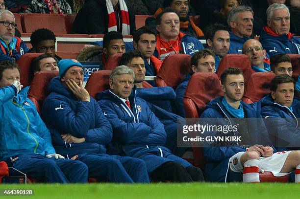 Arsenal's French manager Arsene Wenger watches from the dug out with unused substitutes Arsenal's English defender Calum Chambers and Arsenal's...