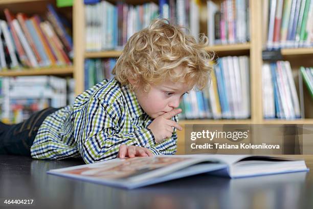 little blond boy reading a book in a library - open day 5 stockfoto's en -beelden