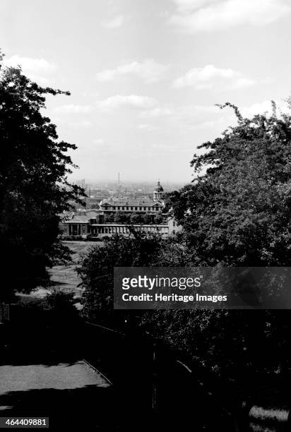Distant view showing part of the Royal Naval Hospital Greenwich, from Greenwich Park, London, c1945-c1965. Trees frame the hospital, with a skyline...