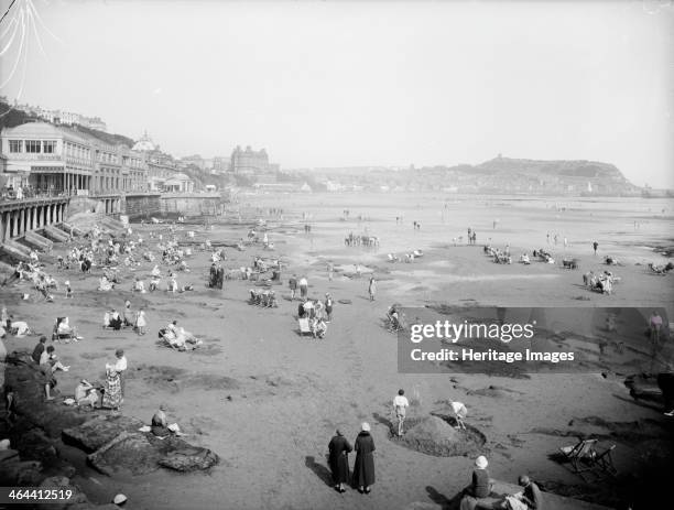 The beach at Scarborough, East Riding of Yorkshire. Holidaymakers enjoy themselves on the beach at Scarborough. Many have deckchairs. Two children in...