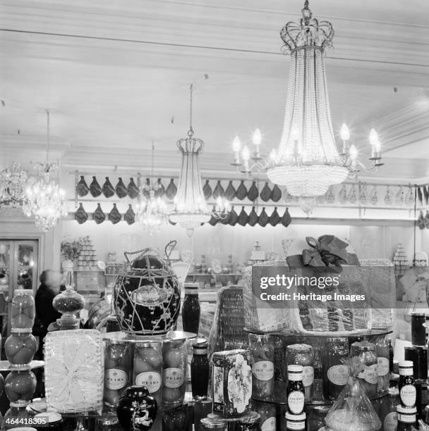 Fortnum & Mason, 181 Piccadilly, London, 1960-1965. A display of luxury groceries in glass jars, tins and baskets under chandeliers.