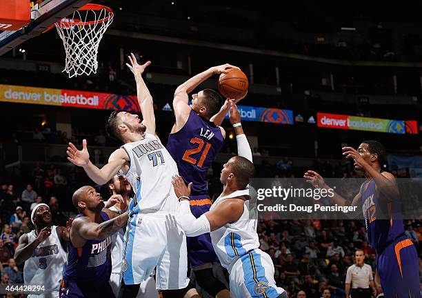 Alex Len of the Phoenix Suns tries to get off a shot against the defense of Joffrey Lauvergne and Randy Foye of the Denver Nuggets at Pepsi Center on...