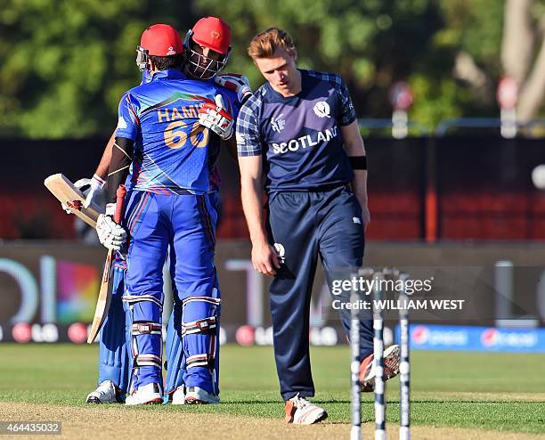 Afghanistan batsmen Hamid Hassan and Shapoor Zadran celebrate as Scotland's Richie Berrington reacts in their 2015 Cricket World Cup Group A match in...