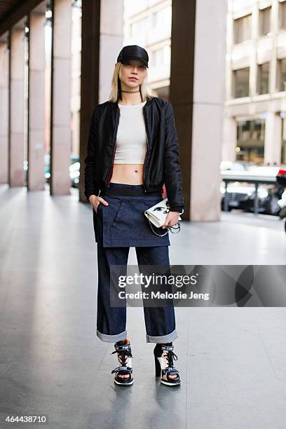 Model Soo Joo Park exits the Fay show in an Acne hat, Aritzia top, Kara Ross bag, and Fay jeans and shoes on February 25, 2015 in Milan, Italy.