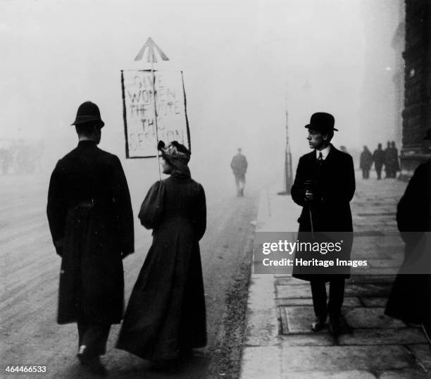 Suffragette demonstrating in Whitehall, London, c1908. Her placard says 'Give Women the Vote this Session'. The arrow at the top of the placard...