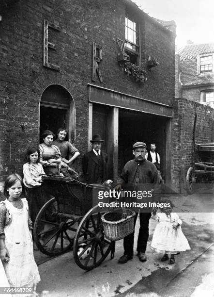 Cat's meat man in an East End street, London, c1901-c1902. The man with his barrow outside a house, holding the hand of a small child. A lump of meat...
