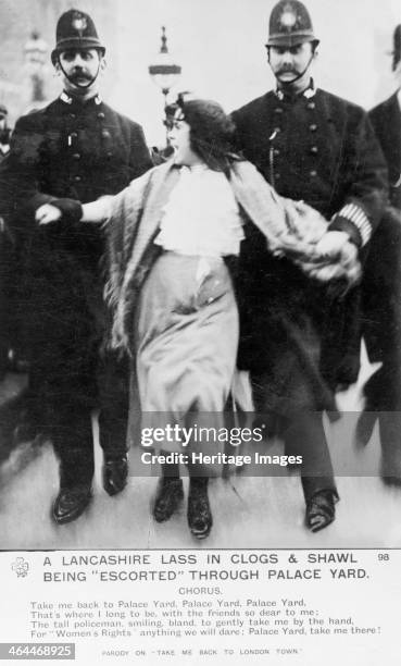 Lancashire lassie' being escorted through the palace yard, Westminster Palace, London, 20th March 1907. A young woman is reluctantly escorted by two...