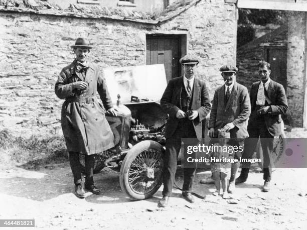 Bedford standing at the front of a car, with onlookers.