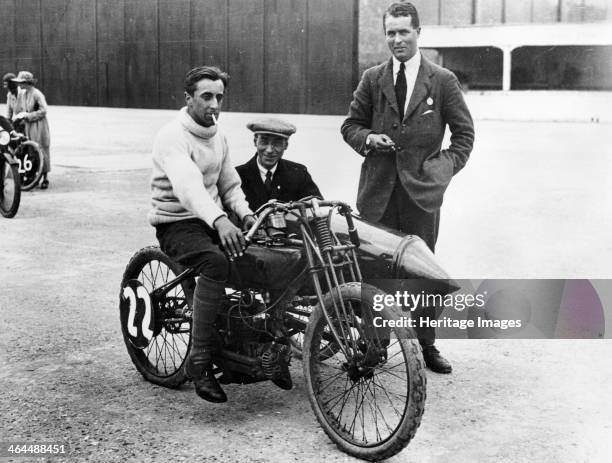 Davidson on a Flat Twin Harley-Davidson, Brooklands, Surrey, 1920. Sitting on the bike smoking a cigarette, with a passenger in the sidecar.