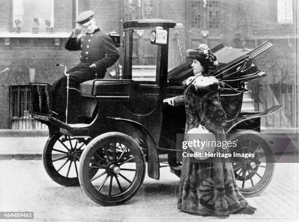 Lillie Langtry modelling a sable motoring coat. Standing next to an electric City and Suburban car. The driver tips his hat to the photographer.