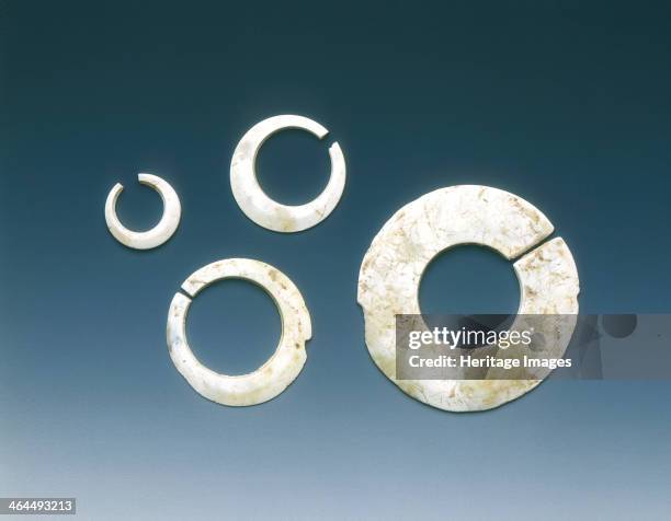 Four altered jade asymmetrical slit-discs, Neolithic, Liangzhu culture, China, c3400-2200 BC. A set of four slit-disc rings of heavily calcified...