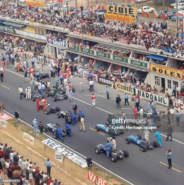 Cars lining up on the starting grid, French Grand Prix, Le Mans, France, 1967. Drivers and team members stand by the cars. A photographer can be seen...