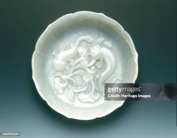 White jade bracketed saucer with two catfish and fungus in relief, Qing dynasty, mid 18th century. A transparent shallow saucer of 6-bracketed...