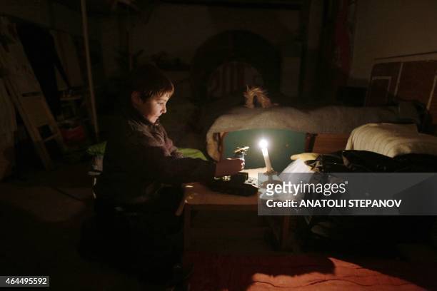 Boy plays with a toy tank as he sits along with his family in a bomb shelter after their house was destroyed in the village of Myronivske near...