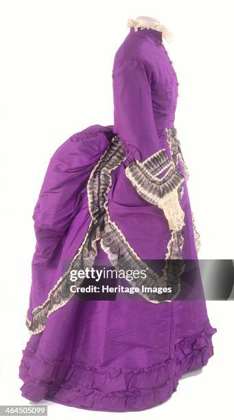 Side view of a fashionable day dress, c1875. The skirt drapery is predominantly at the back of the dress where it was supported by a bustle, a false...