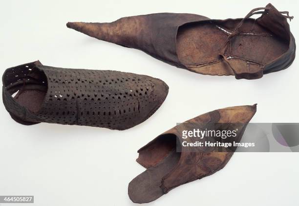Leather shoes, medieval. One of the shoes is pierced and it is not as pointed as the others. The one that looks like a flip-flop has a leaf-design on...