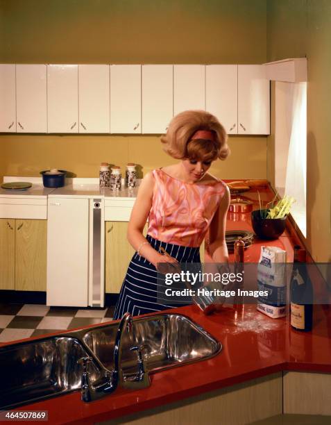 Kitchen scene, Warwick, Warwickshire, 1966. A housewife cooking in her new kitchen. The kitchen is the new fitted 'American' style with matching...