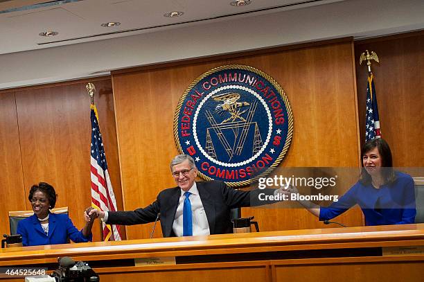 Thomas "Tom" Wheeler, chairman of the Federal Communications Commission , center, holds hands with commissioners Mignon Clyburn, left, and Jessica...