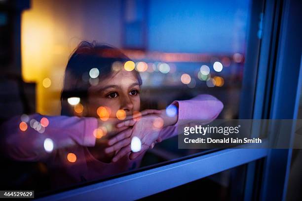 girl at window with reflected city lights - looking through window stockfoto's en -beelden