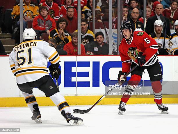 David Rundblad of the Chicago Blackhawks looks to pass against Ryan Spooner of the Boston Bruins at the United Center on February 22, 2015 in...