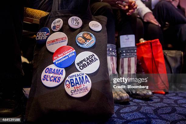 Anti U.S. President Barack Obama buttons hang on a bag in front of attendees listening to Senator Ted Cruz, a Republican from Texas, not pictured,...