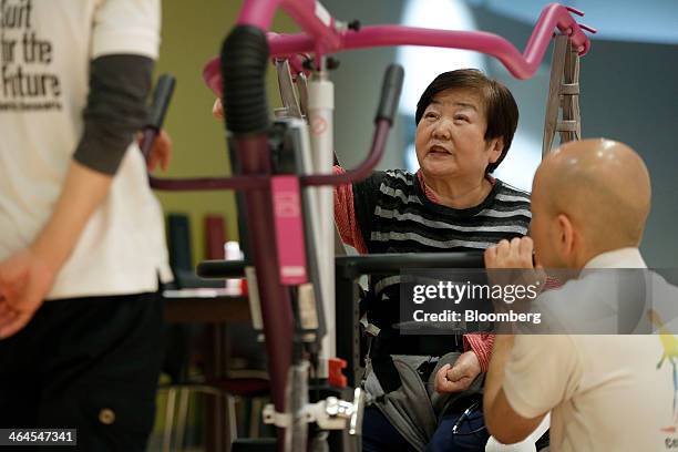 Mieko Kawakami, who suffers from gait disorder due to partial paralysis, center, speaks with physiotherapists Masato Hasegawa, left, and Koji Ono,...