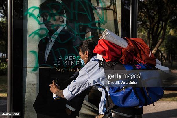 Demonstrator paints an ad paints an ad on a billboard during a protest in Mexico City, on February 26, 2015 to demand justice for 43 students from...