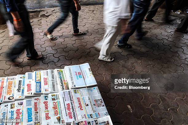 Commuters walk past a newspaper stall outside Chhatrapati Shivaji Terminus railway station during the morning rush-hour in Mumbai, India, on...